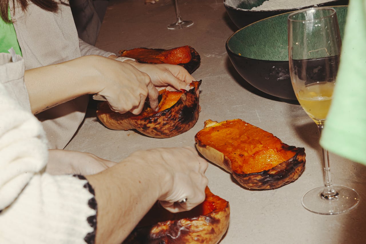 Services Close-up of hands scooping roasted squash in a cozy kitchen setting in Barcelona.