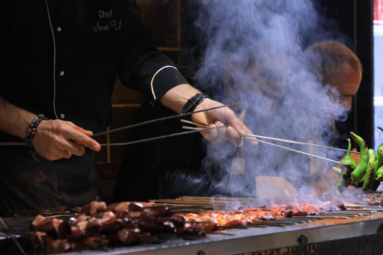 Services Chef expertly grills skewered meat and vegetables over an open flame, surrounded by smoky aroma.